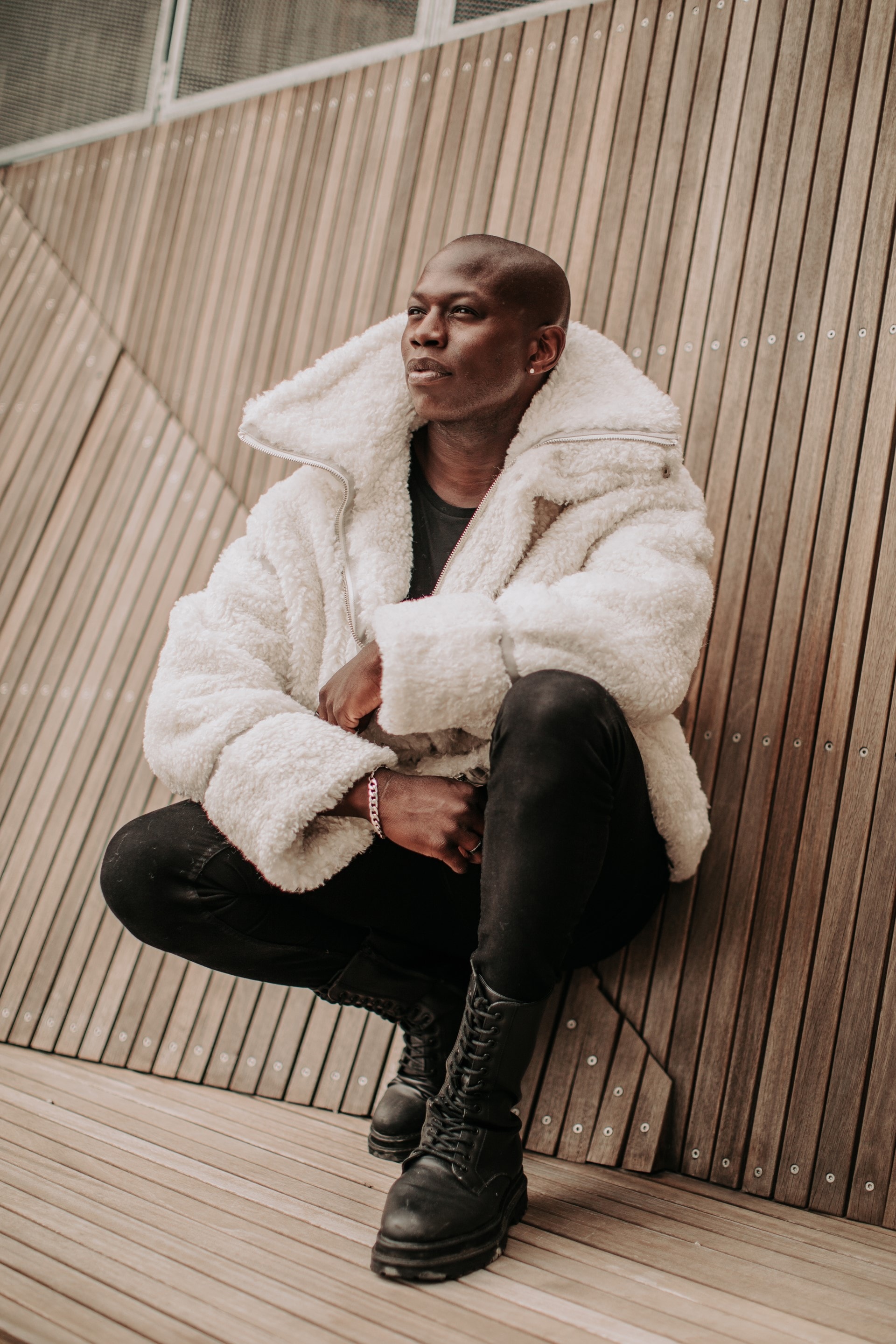 Man sitting on wooden stairs in white fluffy jacket