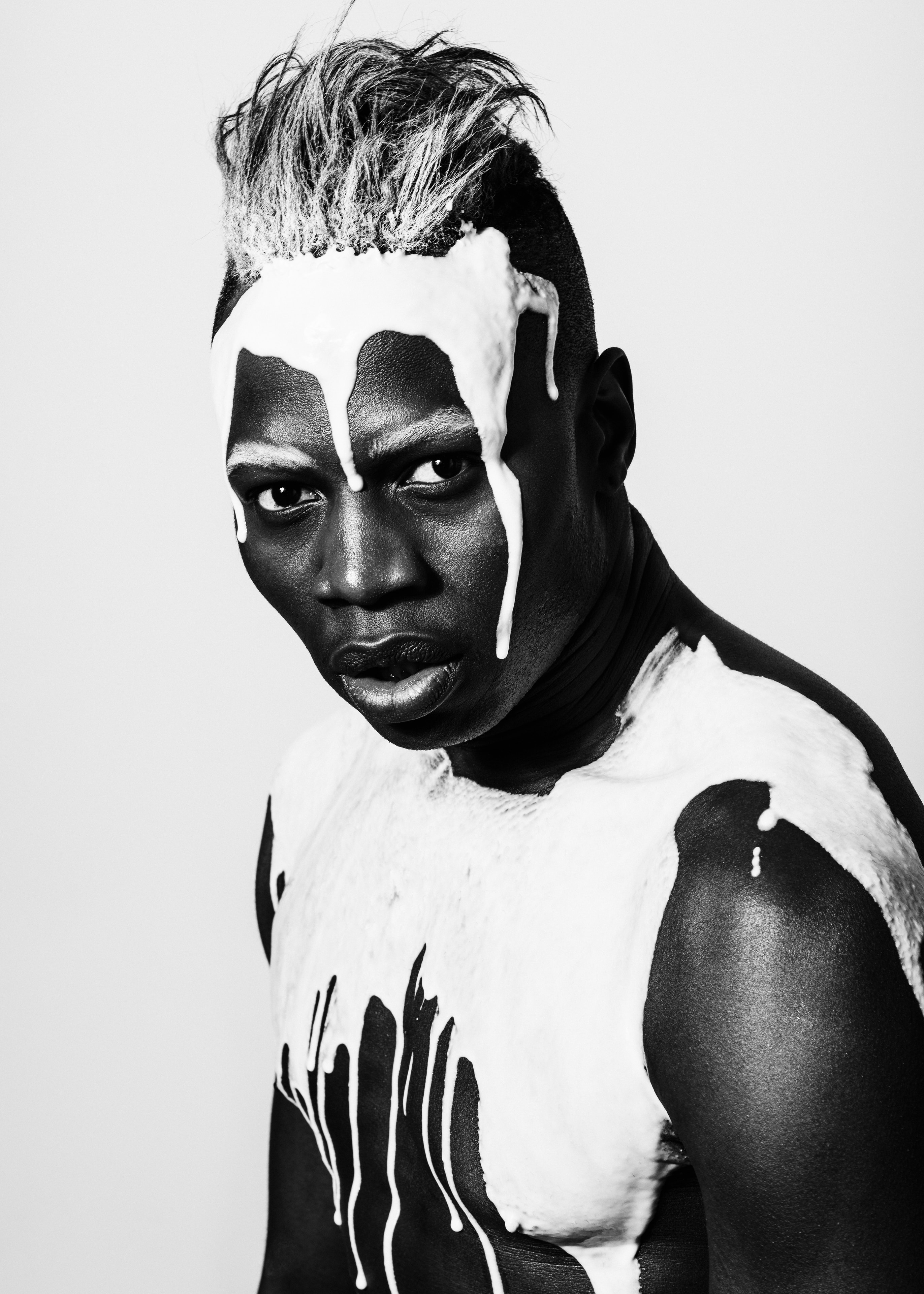Black and white editorial portrait with white paint over face